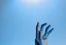 Robotic hand with articulated fingers reaching towards the sky on a blue background.
