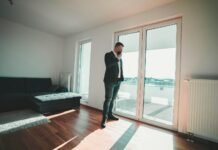 man in black suit standing near glass door