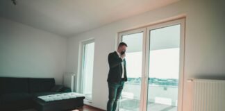 man in black suit standing near glass door